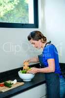 smiling woman tossing a salad for dinner