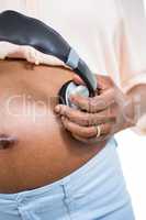 Pregnant woman holding headphone on belly