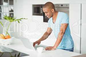 Smiling man using laptop on the counter