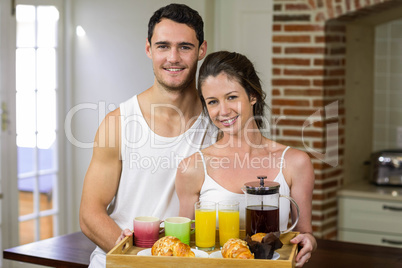 Happy couple carrying breakfast tray in kitchen