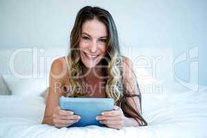 smiling woman lying on her bed on her tabet