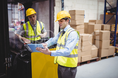 Warehouse worker talking with forklift driver