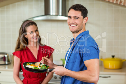 Couple holding pan of vegetables and smiling
