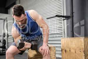 Muscular man lifting dumbbell on wooden block
