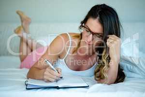 woman with glasses writing in a book