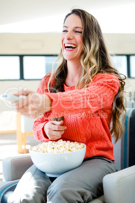 smiling woman eating popcorn and watching tv