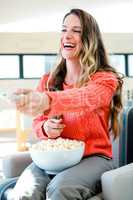 smiling woman eating popcorn and watching tv