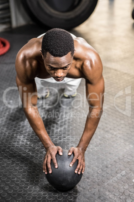 Muscular man doing push up with medicine ball