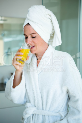 woman wearing a dressing gown drinking a glass of juice