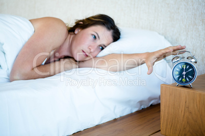 tired woman reaching out to turn off her alarm
