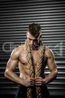 Shirtless man with battle rope around neck