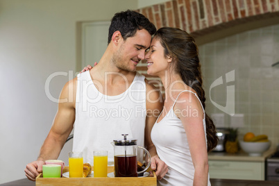 Happy couple carrying breakfast tray in kitchen