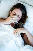 sick woman blowing her nose into a tissue