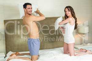 Portrait of young couple playing pillow fight