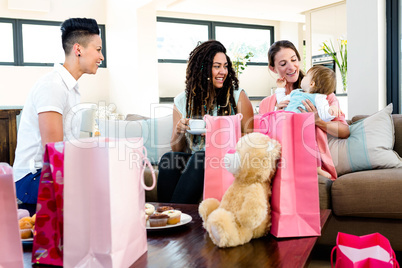 3 women smiling at a baby surrounded by gifts