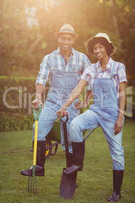 Smiling couple holding shovel and rake