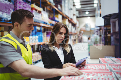 Warehouse manager and worker looking at tablet
