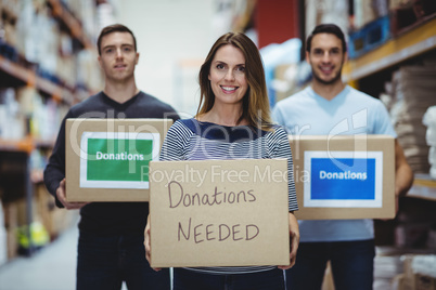 Volunteers smiling at camera holding donations boxes