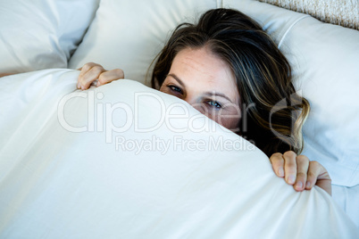 smiling woman hiding behind her duvet