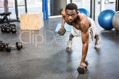 Muscular man doing push up with dumbbells