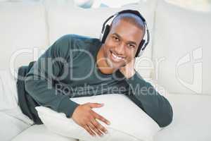 Handsome man lying on the sofa with headphones