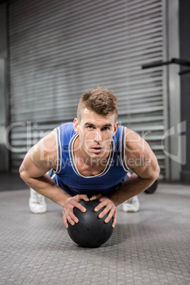 Muscular man doing pull up with medicine ball