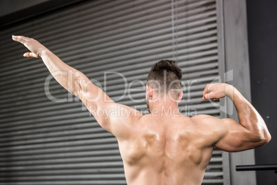 Rear view of shirtless man flexing muscles