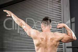 Rear view of shirtless man flexing muscles