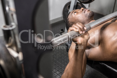 Shirtless man lifting barbell on bench