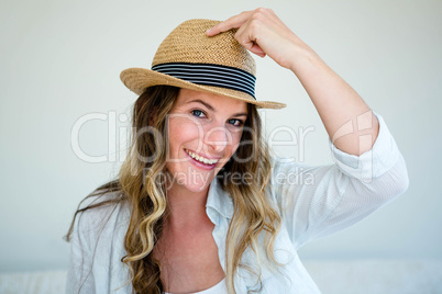 woman wearing a straw fedora smiling into the camera