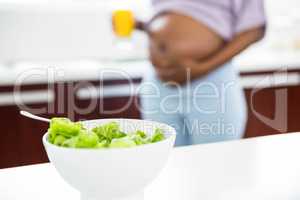 Pregnant woman in kitchen with salad on table