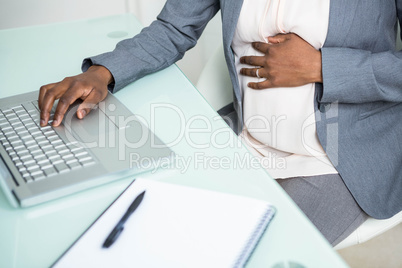 Pregnant businesswoman working on laptop