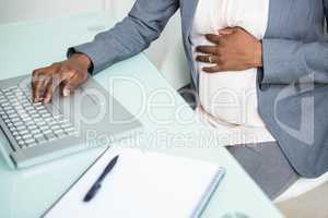 Pregnant businesswoman working on laptop