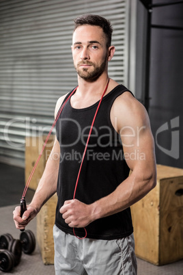 Muscular man holding rope around his neck