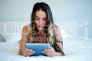 woman lying on her bed on her tablet