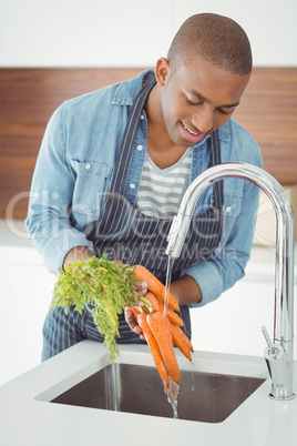 Handsome man washing carrots