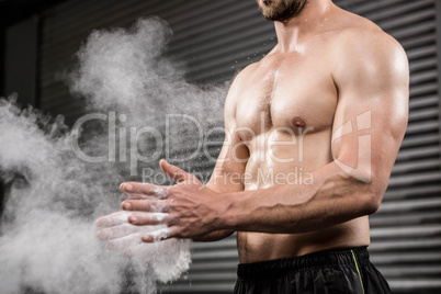 Mid section of shirtless man clapping hands with talc