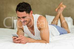 Young man lying on bed with his phone