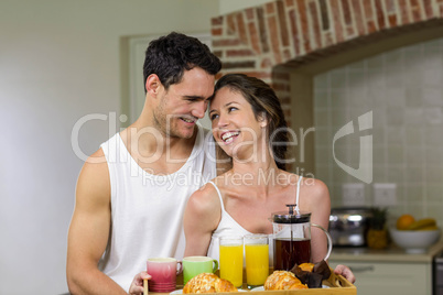 Happy couple holding a tray of breakfast