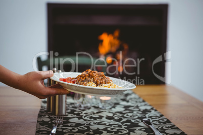 Person putting spaghetti on table