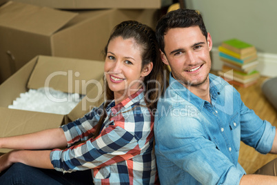 Young couple sitting back to back in their new house