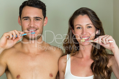 Young couple brushing their teeth at home