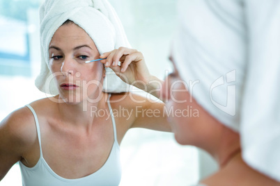woman using a cotton bud to fix her mascaara