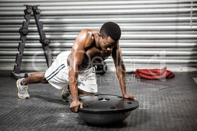 Muscular man doing push up on bosu ball