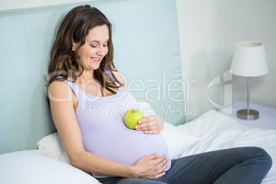 Pregnant woman holding an apple on her bump