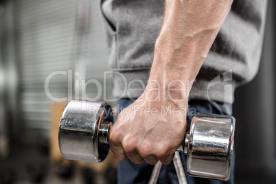 Muscular man with grey jumper holding dumbbell