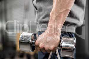 Muscular man with grey jumper holding dumbbell