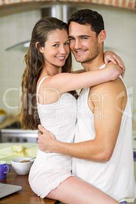 Young couple cuddling on kitchen worktop