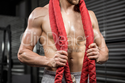 Mid section of shirtless man with battle rope around neck