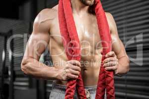 Mid section of shirtless man with battle rope around neck